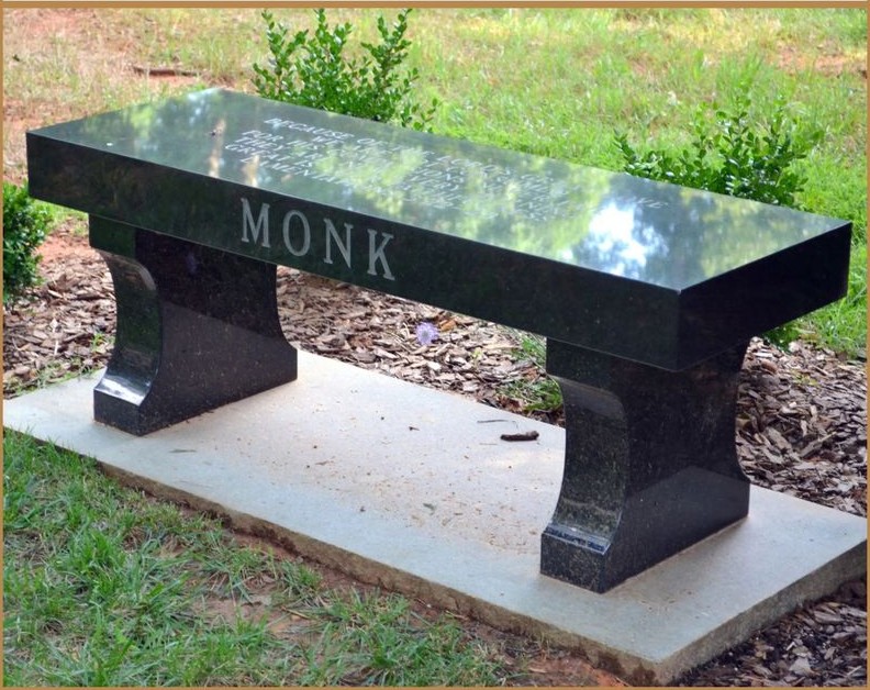 A black granite memorial bench lettered MONK
