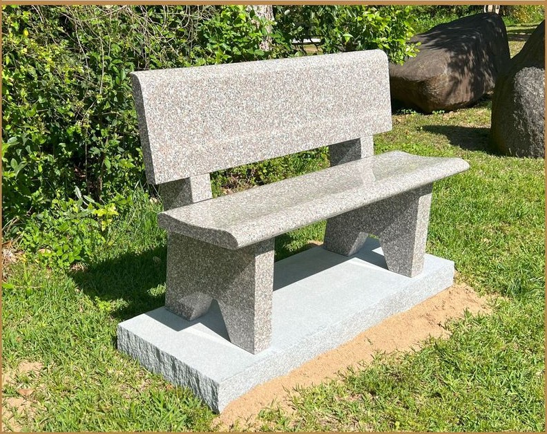 A white granite memorial bench with a curved back rest