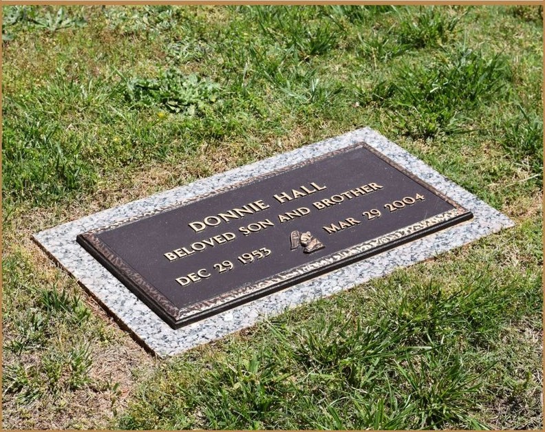 A bronze flat marker mounted on a granite base, set in the grass