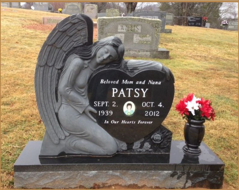 A carved granite angel resting against a polished black memorial stone