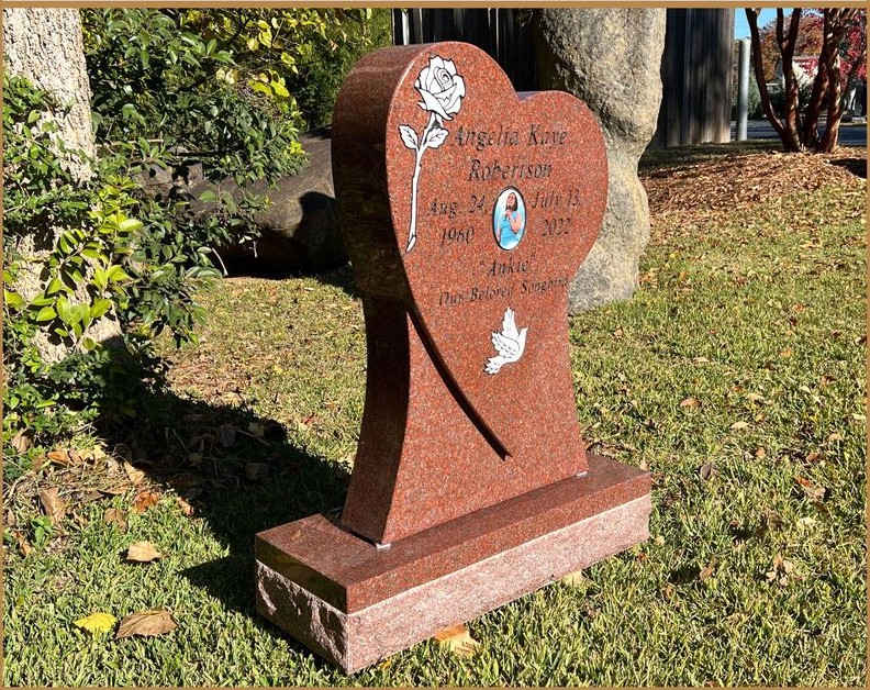 A red granite heart monument with carved detail