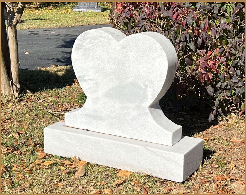A white granite heart monument standing in grass