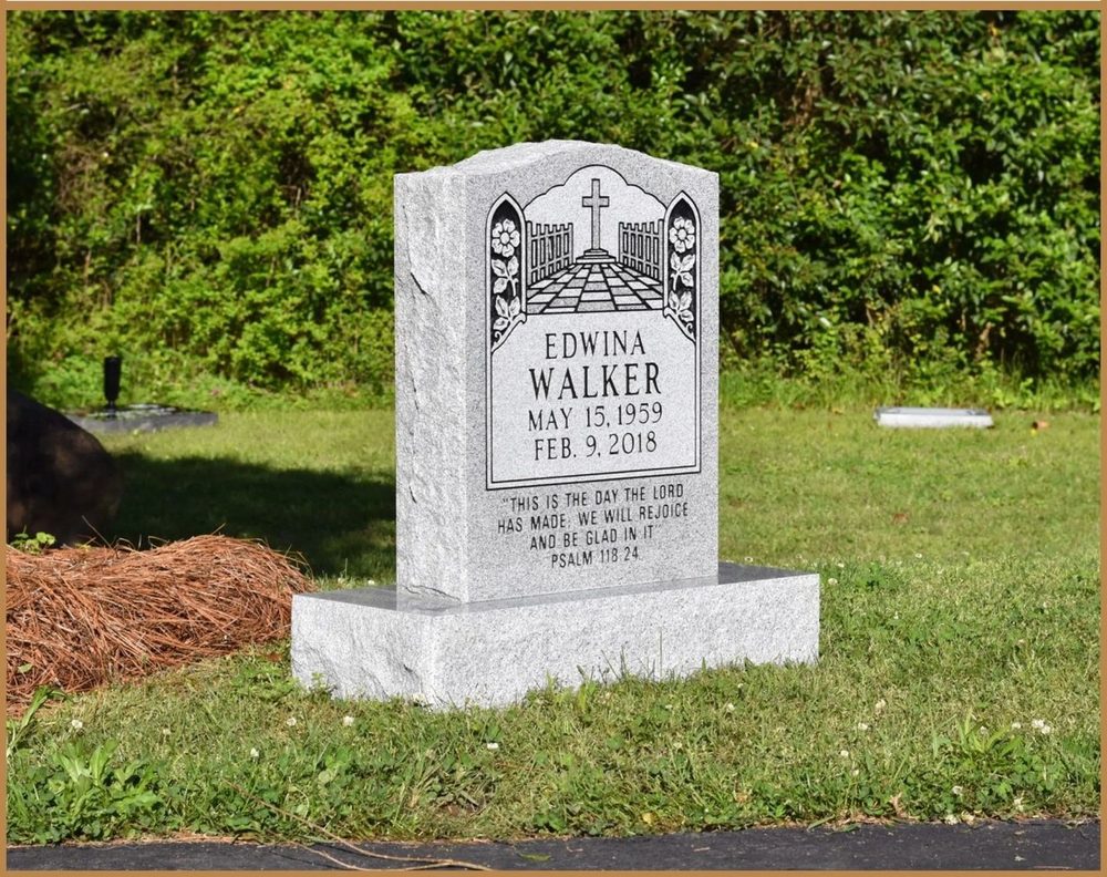 A grey upright monument with carved detail above the inscription